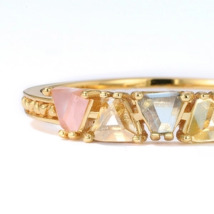 Détail macro d'une bague en or 9K avec pierres multicolores triangulaires et bord perlé