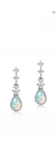 Macro shot of S925 silver earrings with triple zircons and pear-shaped fire opal drops