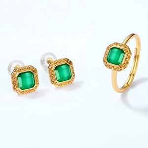 Detail shot of vintage gold jewelry set with emerald green stones and geometric patterns