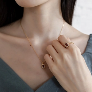 Detailed view of rectangle red garnet jewelry set including necklace and ring on model