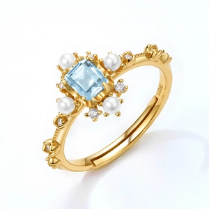 Dettaglio anello in argento S925 dorato con topazio blu, perle e fascia floreale ornata