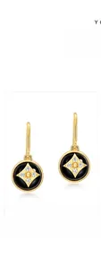 Macro shot of gold-plated clover earrings featuring black onyx and star diamond accents