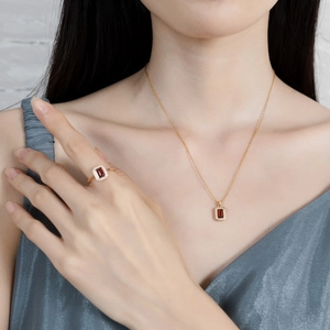 Macro view of garnet ring and necklace set with rectangle cut stones and diamond halo
