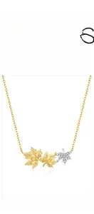 Detailed close-up of mixed-metal maple leaf pendant with pavé zirconia on a gold chain