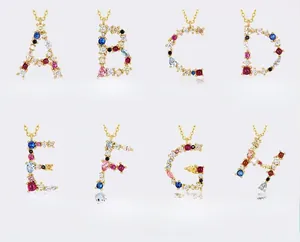 Dettaglio macro di ciondoli in argento S925 dorato con zirconi colorati lettere A-H