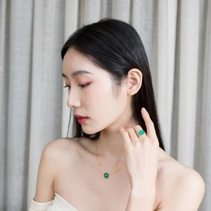 Détail d'une parure en plaqué or avec pierres de malachite vertes rondes sur un mannequin