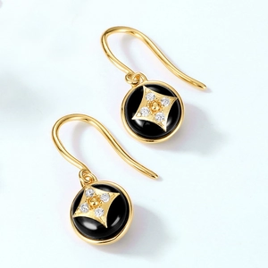 Macro shot of gold four-pointed star motif on black onyx dangle earrings set