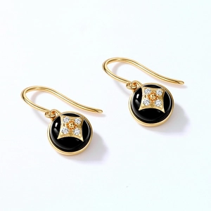 Close-up of gold clover earrings with black onyx stone and sparkling cubic zirconia stars