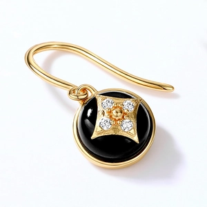 Macro detail of a black onyx clover earring with a gold star and white zircon accents