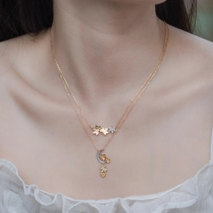 Close-up of layered 925 silver necklace with maple leaves and moon pendant set with zircons