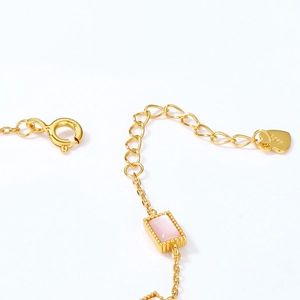 Macro detail of S925 sterling silver stamp on golden chain with pink shell stone