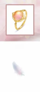 Macro detail of bird-inspired 925 silver ring with pink crystal and golden feather texture