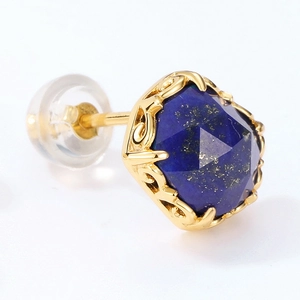 Macro shot of faceted lapis lazuli stud earring with vintage hollow patterned gold base