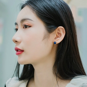 Close-up of lapis lazuli stud earring with gold-plated vine design on woman's ear