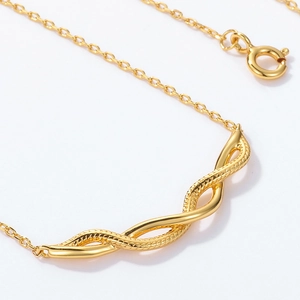 Detailopname van een vergulde 925 zilveren gedraaide hanger aan een fijne schakelketting