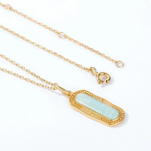 Détail d'un pendentif géométrique en amazonite avec gravure vintage dorée