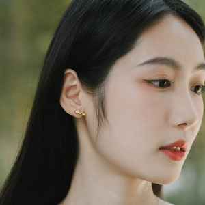 Boucles d'oreilles poisson dorées avec cristaux portées par un mannequin en nature
