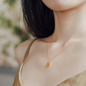 Dettaglio di un ciondolo foglia vintage con citrina gialla su catena placcata oro