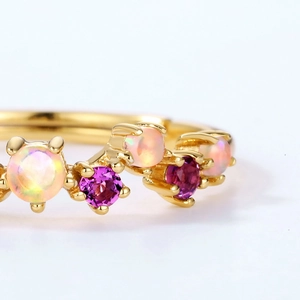 Macro shot of gold plated ring with pink gemstones and iridescent opal stones