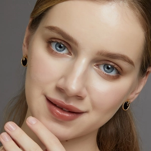 Close-up of vintage golden snake-style earrings with oval black onyx worn by a model