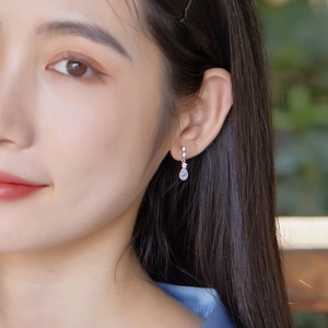 Detail of pear-cut opal earrings with diamonds on a model for a refined look