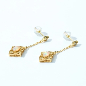 Detailed macro view of vintage opal drop earrings with intricate gold filigree pattern