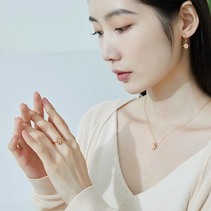 Detail of elegant gold-toned starburst jewelry set with white zircon on a female model