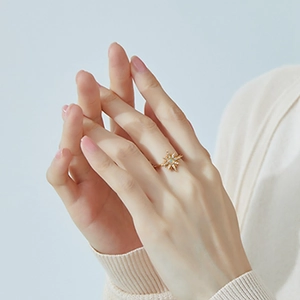 Detailed close-up of a gold sunburst ring with opal and zircon on a model's hand