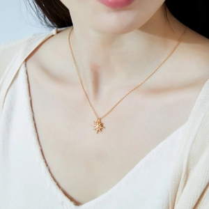 Elegant gold necklace with starburst pendant and opal stone worn by an Asian model
