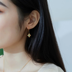 Elegant gold drop earrings with opal-like stones and diamond accents on model