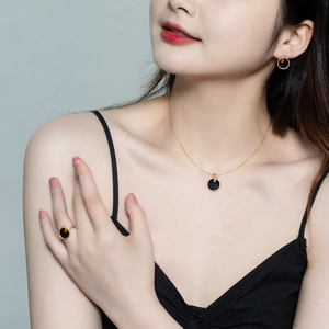 Detail shot of a minimalist gold and black onyx jewelry set worn by a fashion model