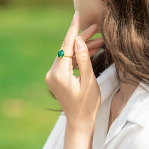 Detailed view of an elegant green agate ring with gold-plated leaf accents on a finger