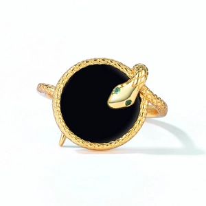 Detailed view of snake ring with black agate, gold finish and green gemstone eyes