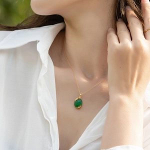 Gros plan du pendentif en agate verte avec détails de feuilles d'or sur le cou