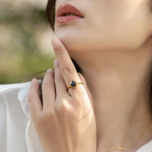 Detail of a retro gold ring with a hexagonal black gemstone on a model's hand