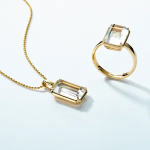 Nahaufnahme von goldenem Schmuckset mit rechteckigem weißem Kristallhalskette und Ring