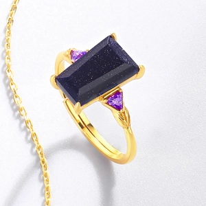 Macro detail of rectangle blue sandstone ring with side purple gems and gold engraved band