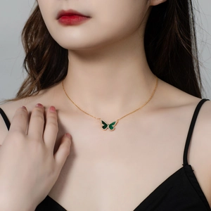 Close-up of a butterfly pendant with green malachite and sparkling crystals on a gold chain