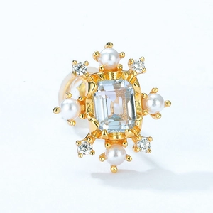 Macro detail of starburst earring featuring rectangular blue topaz and white pearls
