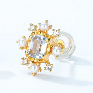 Elegant gold snowflake stud earrings with blue topaz and pearls on white background