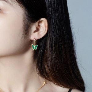 Elegant gold butterfly earrings with green malachite pendant shown on a model