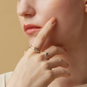 Irregular wave gold ring set with blue sapphire gemstone on elegant female model finger
