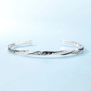 Minimalist geometric twisted silver bracelet with retro textured relief and open design