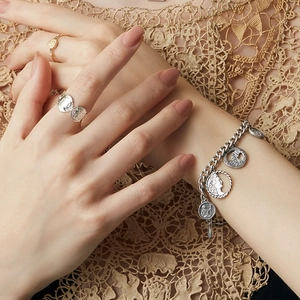 Macro detail of vintage silver coin relief pendants on a chunky chain bracelet