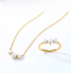 Detailed close-up of 925 silver gold-plated jewelry set with three white pearls on white background