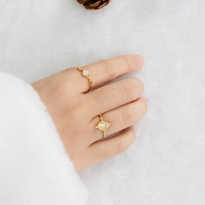 Close-up of elegant gold opal rings with diamonds on a soft white textured background