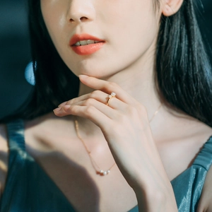 Close-up of elegant gold pearl ring and matching necklace set on a female model