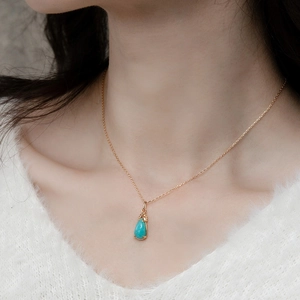 Close-up of S925 silver leaf pendant with amazonite on a gold necklace worn by a model