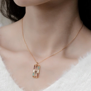 Artistieke gouden hanger met kleurrijke edelstenen gedragen door een model