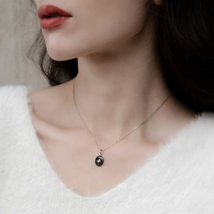 Détail du collier en argent S925 avec pendentif agate noire et étoile dorée sur le cou